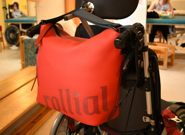 rollial Modell Robin in rot am Rollstuhl am Griff befestigt
